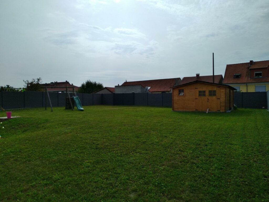 entretien d'espace vert : une grand jardin de gazon vert tondu avec jeux pour enfant et cabane de jardin en bois